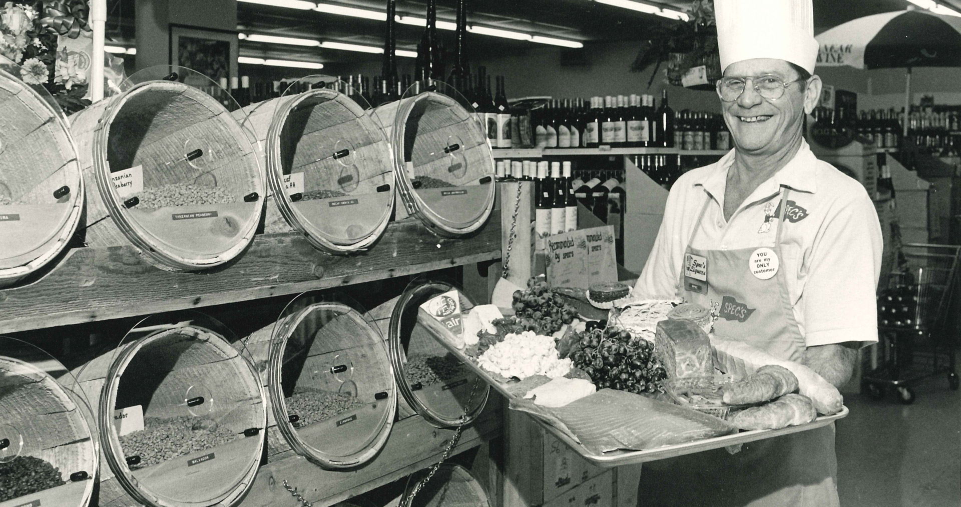 Black and white photograph of a man holding a meat and cheese tray